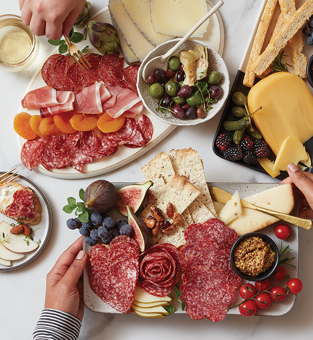 Charcuterie meats cheeses and fruit on a black slate