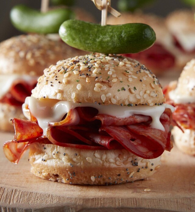 Salami sliders with pickle garnish on a cutting board