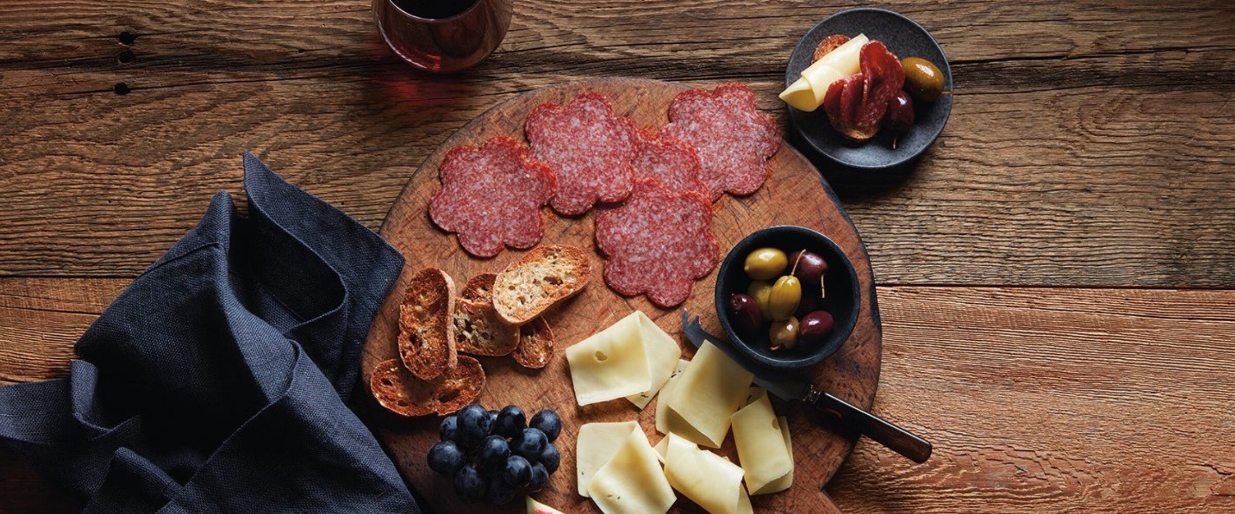 flower shaped sliced meat with cheese and figs on a board