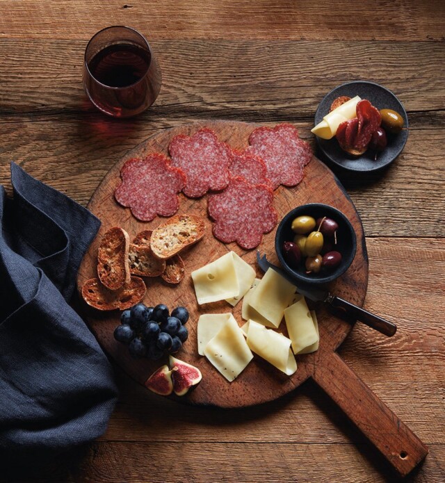 flower shaped sliced meat with cheese and figs on a board