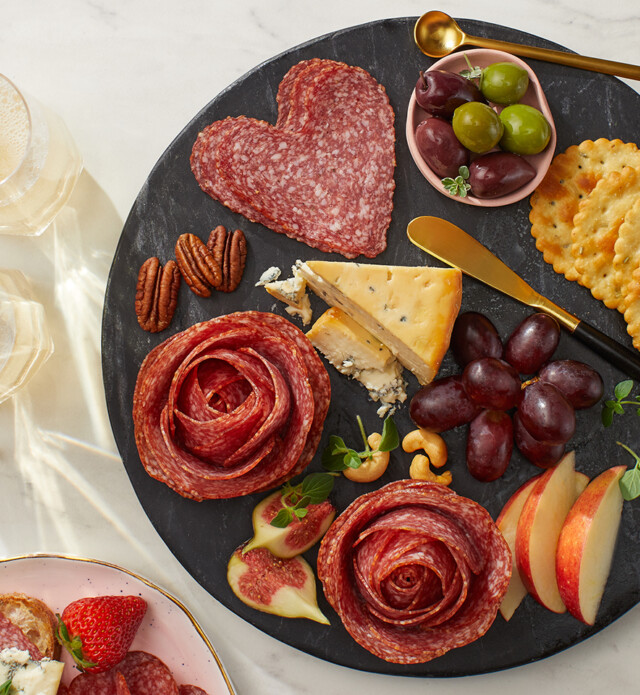 flower shaped sliced meat with cheese and figs on a board