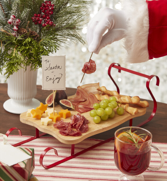 Charcuterie board with Santa taking some meat on a pick in hand