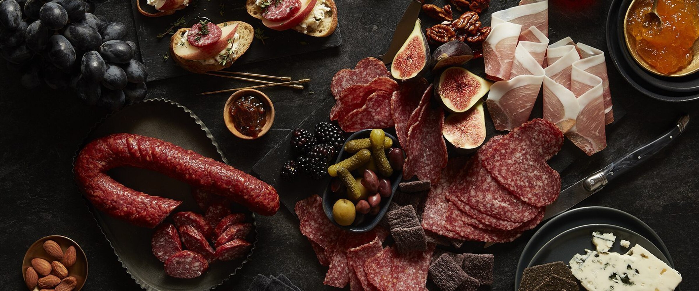 charcuterie meats, cheeses and fruits on a black slate