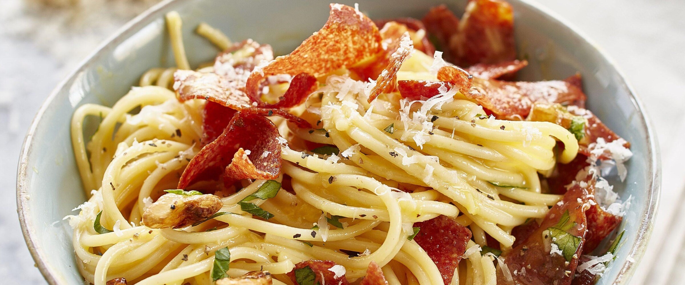 Salami on pasta in a white bowl