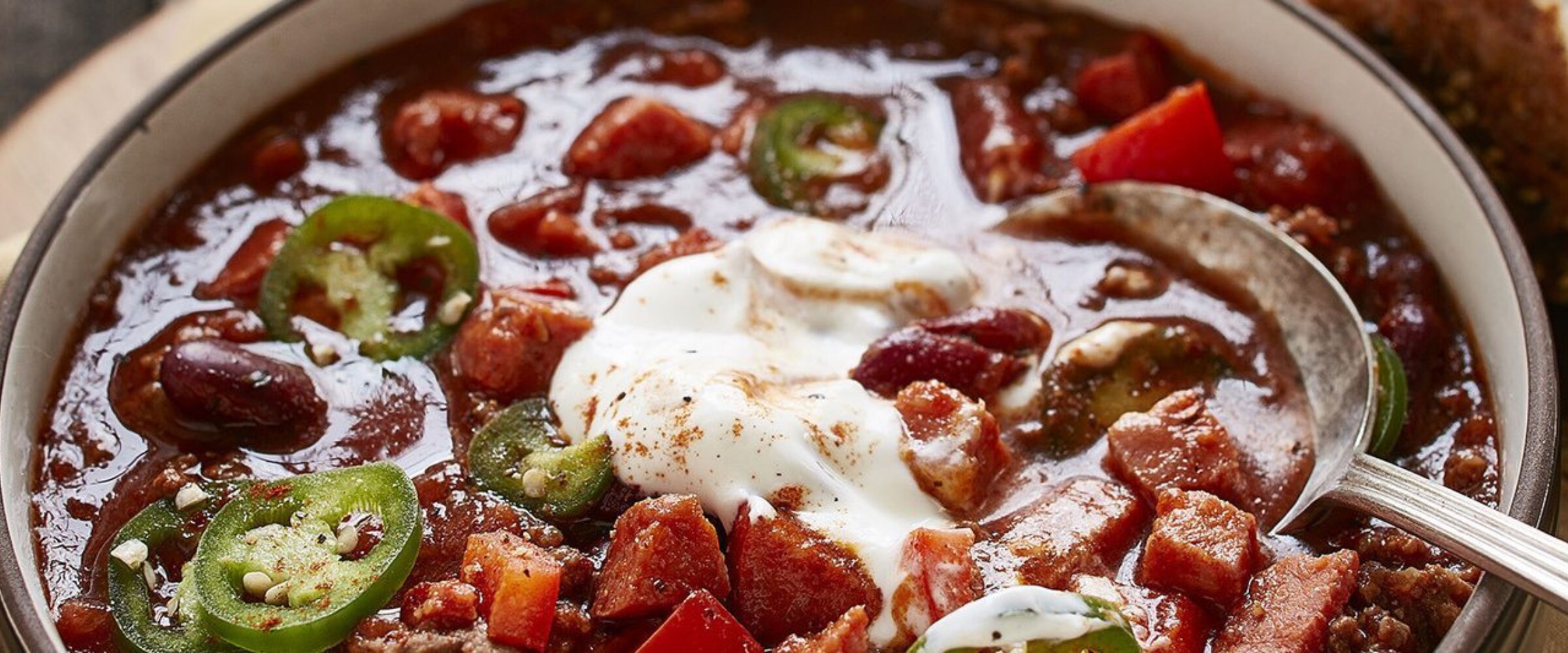 Chorizo and beef chilli with sour cream on top in a bowl