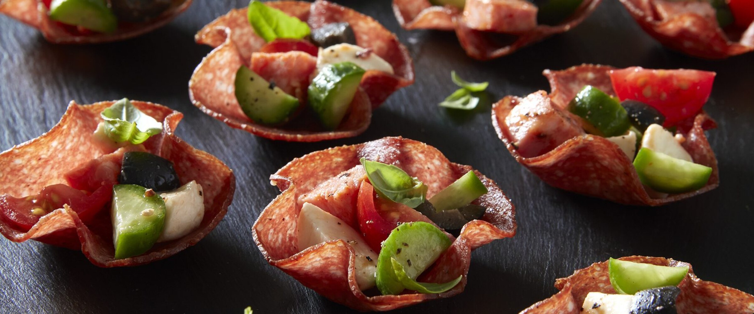 Salami flower cups with antipasto on a black slate