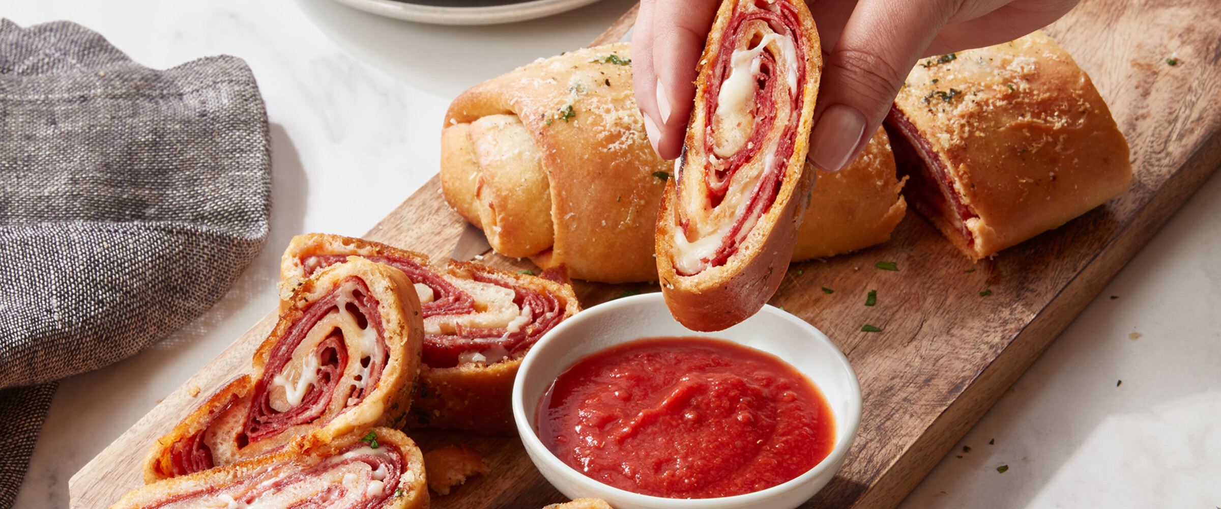 hand dipping stromboli into marinara sauce