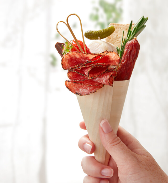 a handholding a cone with charcuterie