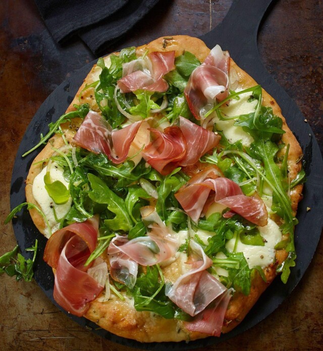 Arugula and prosciutto pizza on a black slate