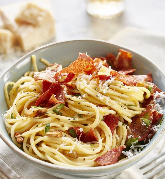 Salami on pasta in a white bowl