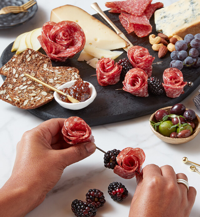 Salami roses on a board with crackers and cheese.