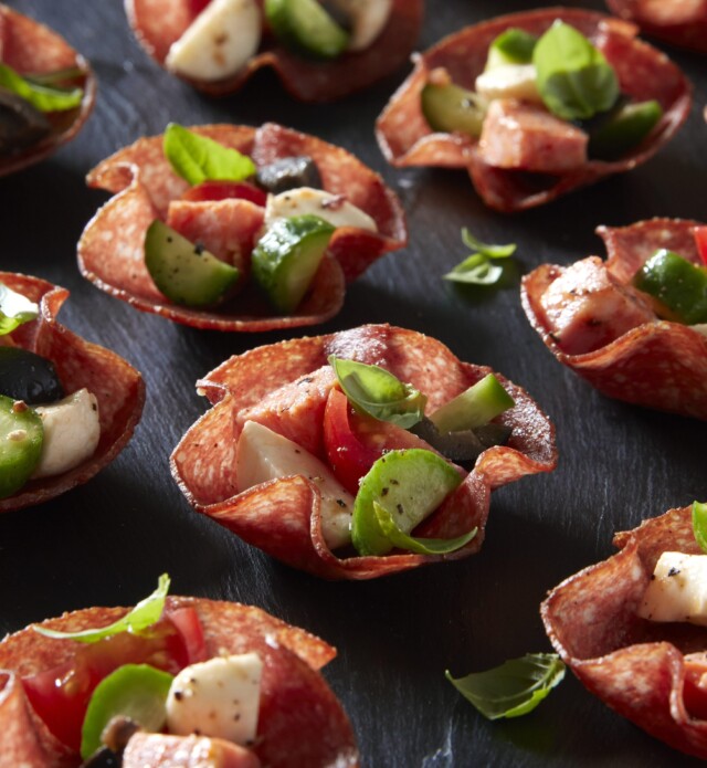 Salami flower cups with antipasto on a black slate