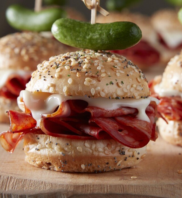 Salami sliders with pickle garnish on cutting board